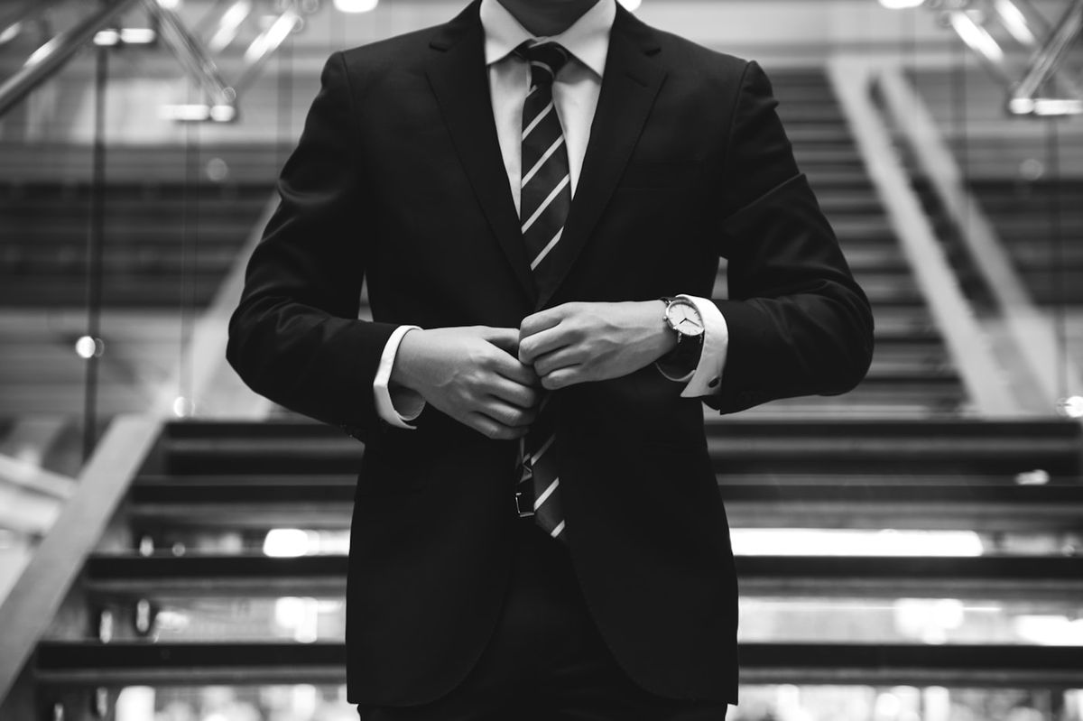 Professional in a dark tailored suit in a modern institutional interior